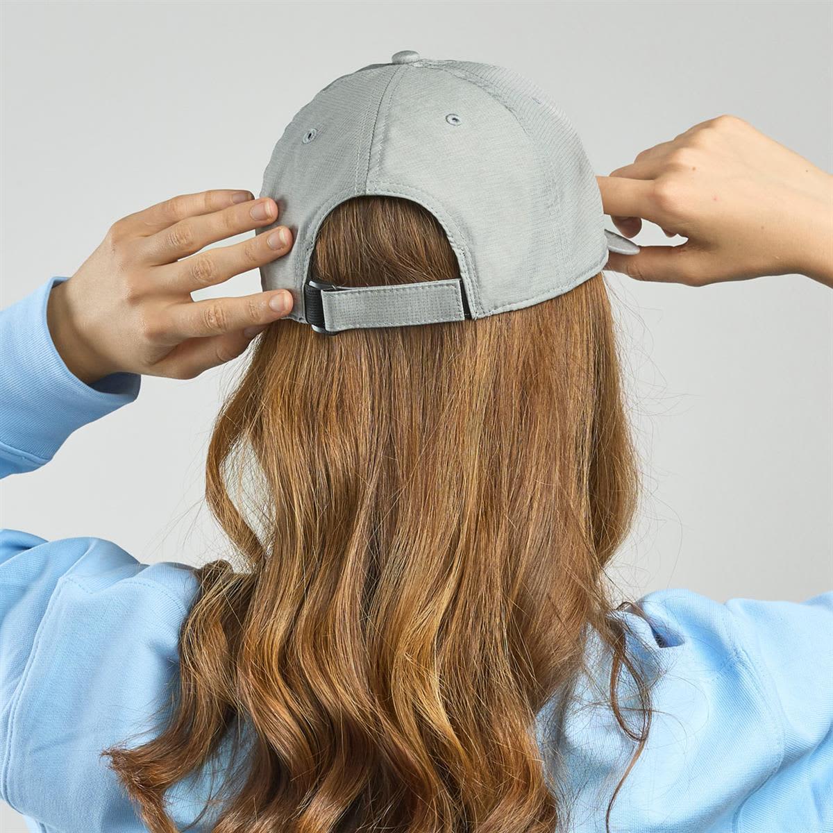 Energy LE-A7700 A cap in light grey, featuring an adjustable strap, being worn by a person with long, wavy hair from the back.