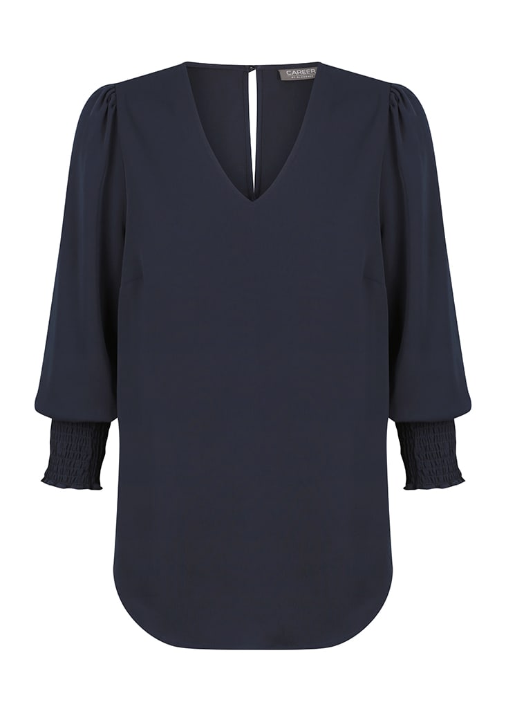 A navy V-neck shirt with puff sleeves and smocked cuffs, featuring a logo at the neckline.