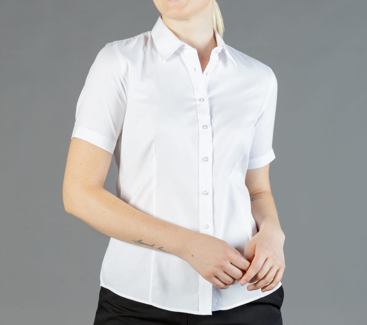 A short-sleeved button-up shirt in white, featuring a classic collar and a fitted design. The shirt has a logo.
