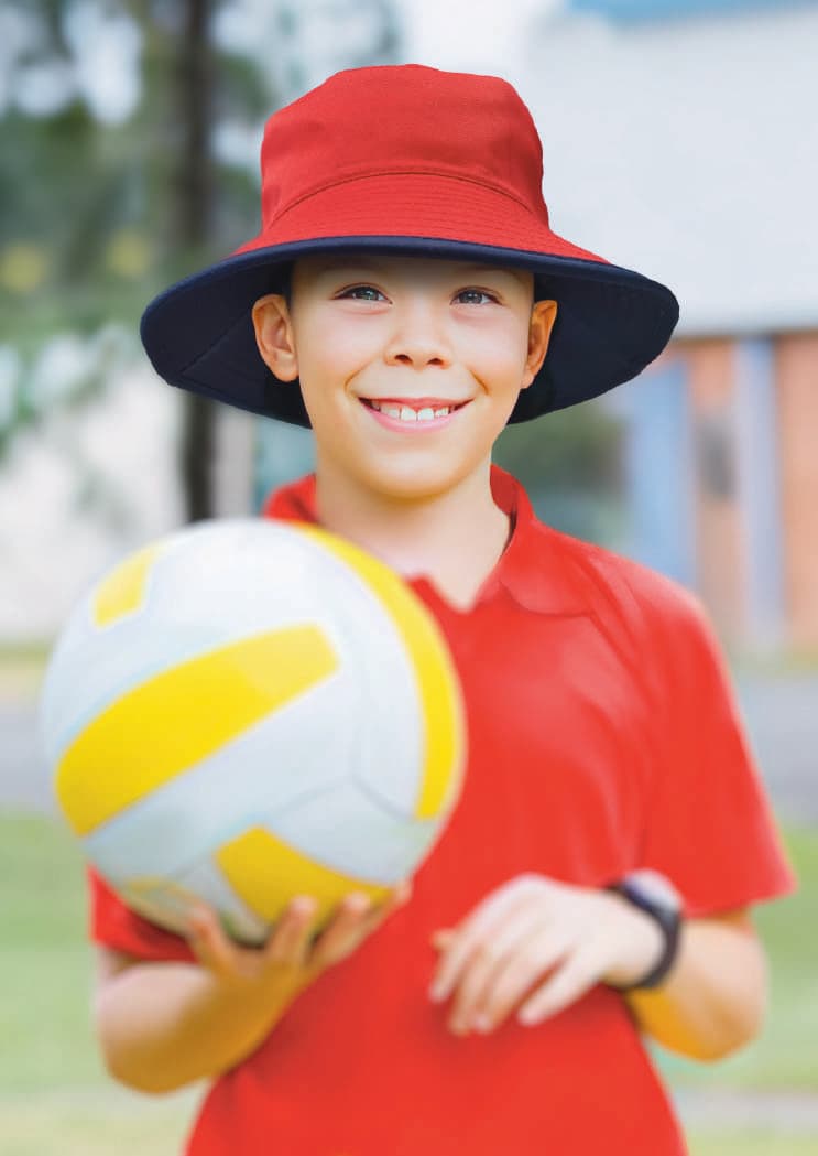 Reversible Breathable Poly Twill Bucket Hat HE-3935 A red and navy reversible bucket hat worn by a smiling boy holding a volleyball, set outdoors.