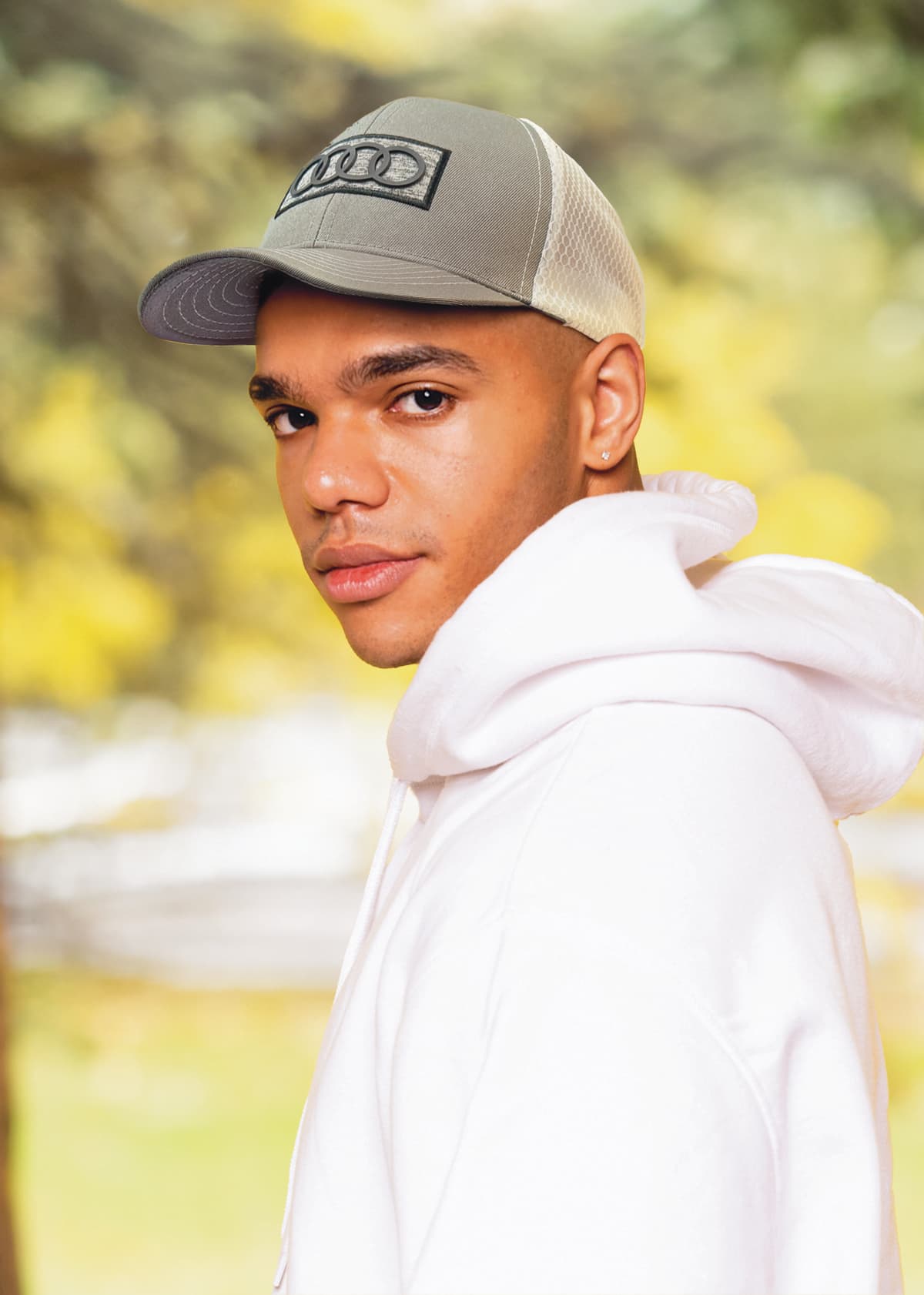 Breathable poly twill with honeycomb mesh HE-3972 A cap with a breathable poly twill and honeycomb mesh in grey, worn by a person in a white hoodie outdoors.