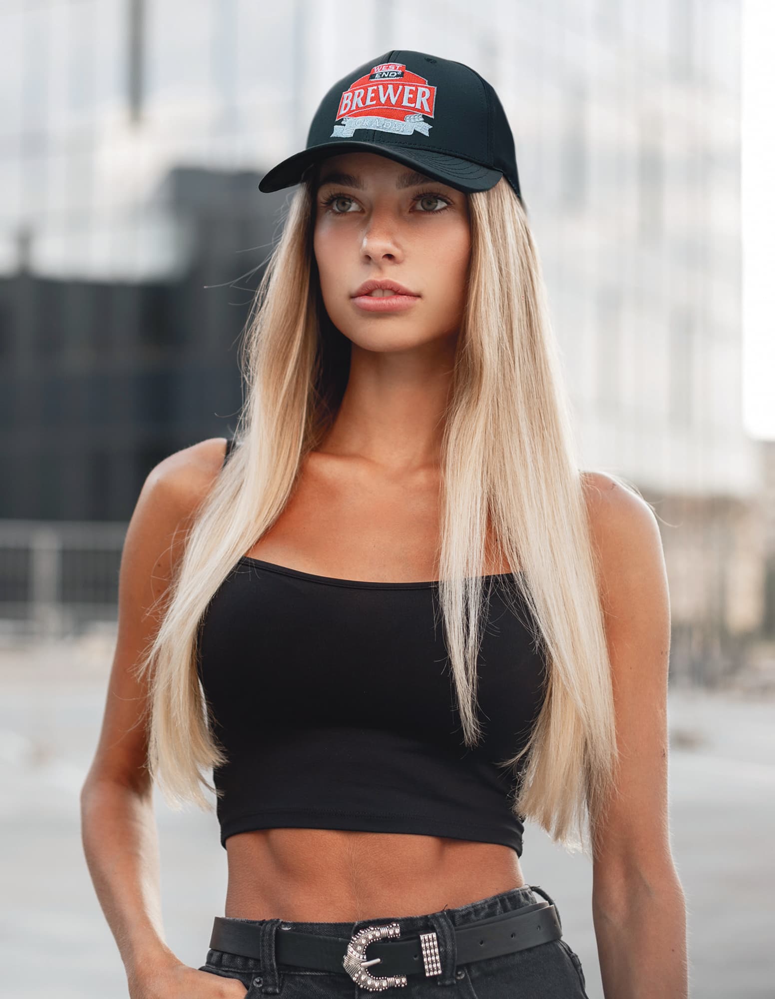 Premium Pioneer Sports Twill HE-3973 A woman with long blonde hair wears a black cap featuring a logo, paired with a black crop top and high-waisted jeans.