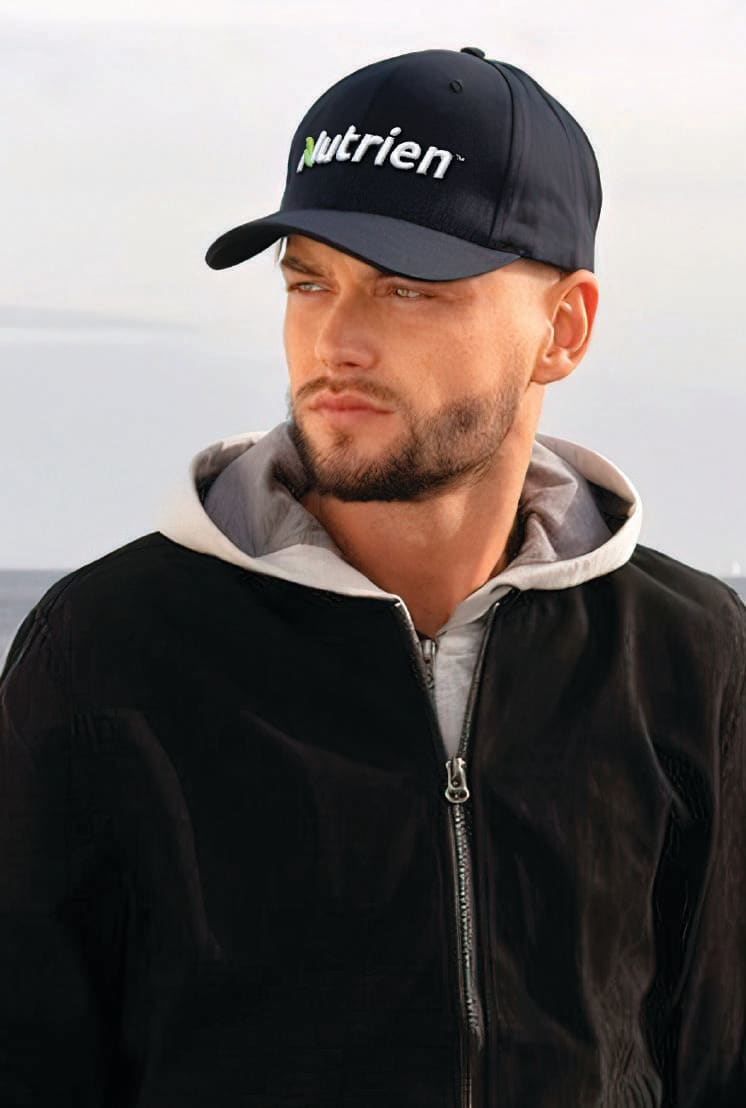 Recycled Breathable Poly Twill Cap HE-3980 A navy cap with a logo, worn by a person in a grey hoodie and black jacket, set against a natural background.