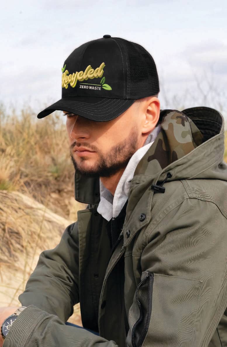 Recycled Breathable Poly Twill with Mesh Back Cap HE-3982 A black cap with a mesh back, featuring a logo, worn by a person in a green jacket outdoors.