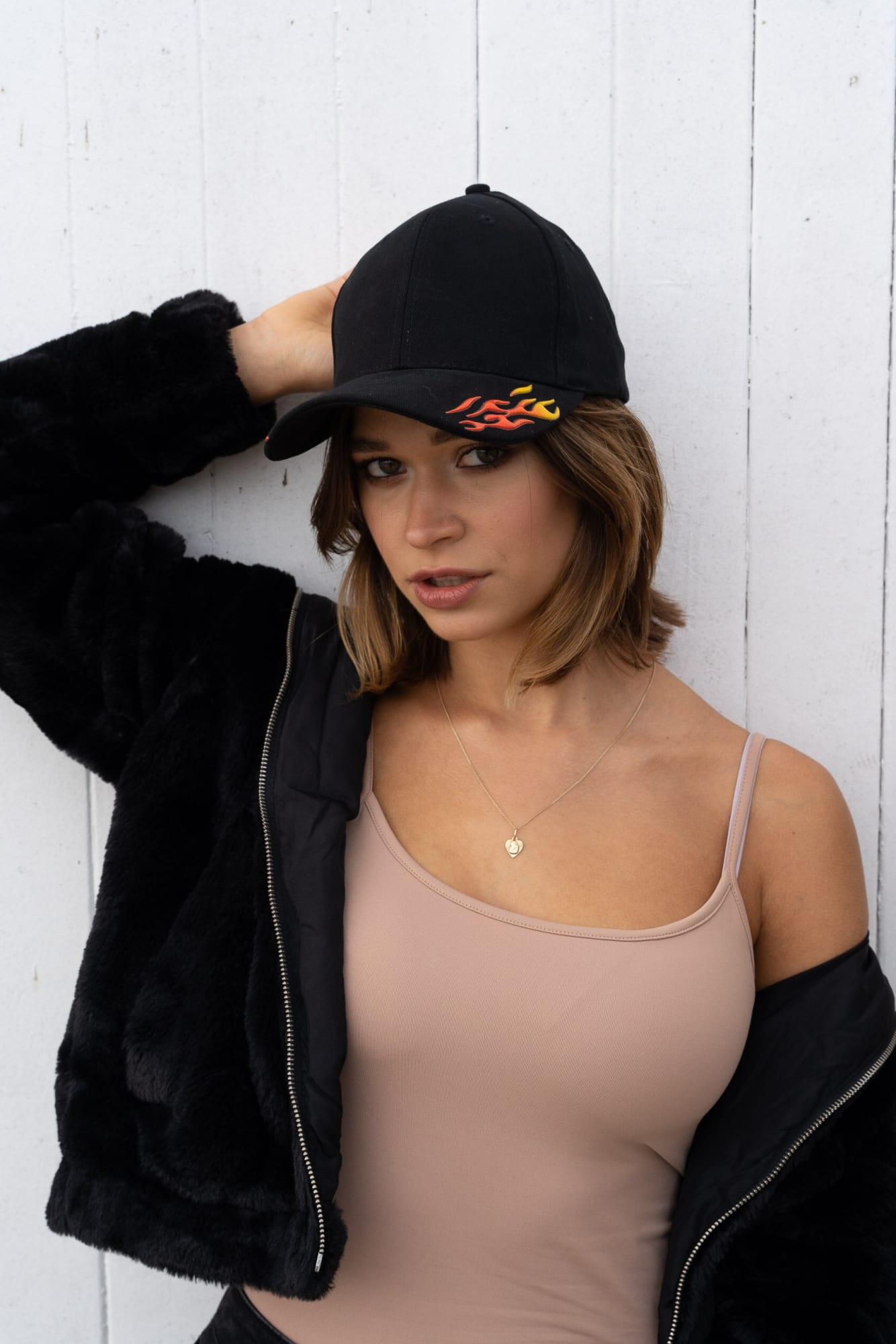 Brushed Heavy Cotton with Sonic Weld Flames HE-4016 A black cap with sonic weld flame design, worn by a woman in a beige tank top and black jacket.