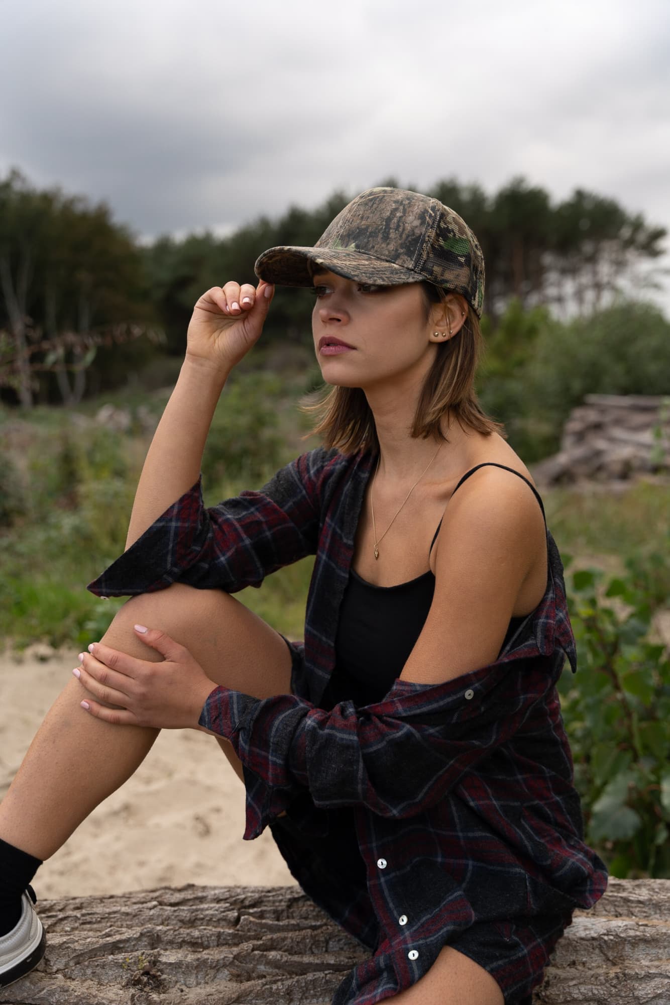 True Timber Camouflage with Camo Mesh Back HE-4059 A young woman wears a True Timber camouflage cap, sitting outdoors in a casual outfit. The background features greenery.