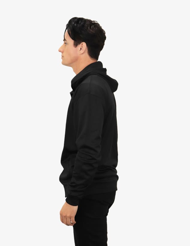 A black hoodie with a front pouch pocket and a hood, worn by a person facing sideways.