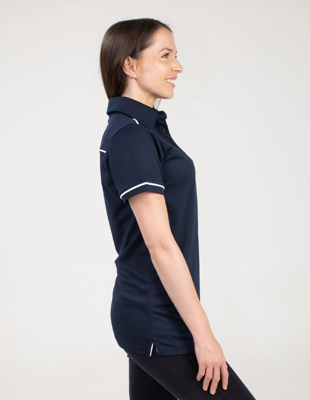 A navy blue polo shirt with white accents and a logo, displayed on a model in profile.