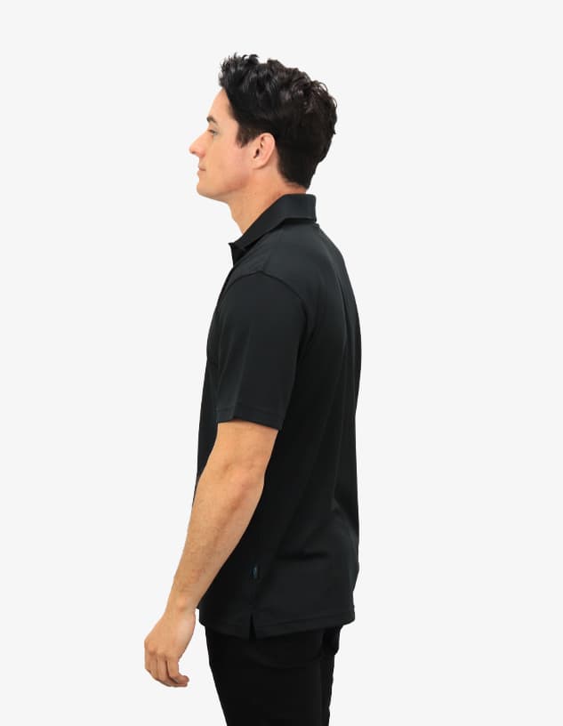 A side view of a black polo shirt worn by a model, featuring a logo on the chest.