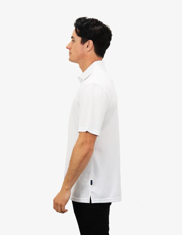 A white polo shirt displayed on a model, featuring a logo and side slits for a modern fit.