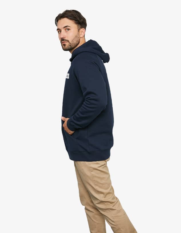 A navy blue hoodie featuring a front pocket and a hood, displayed on a model standing sideways.