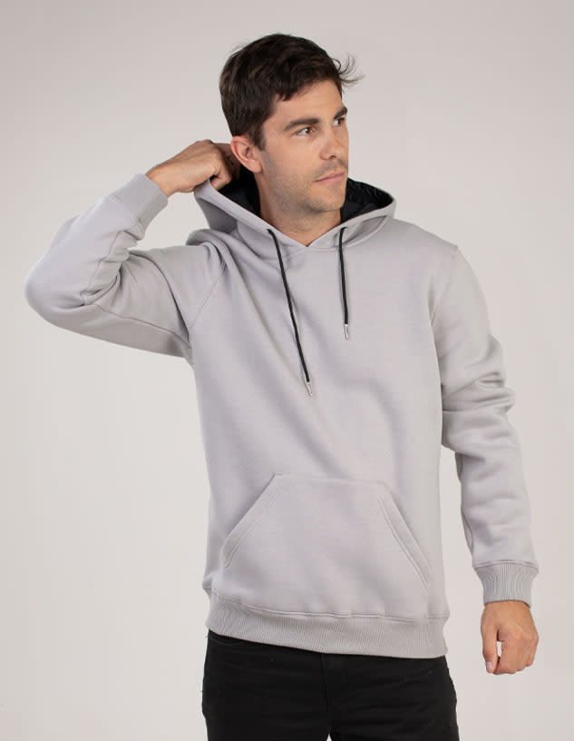 A grey hoodie with a kangaroo pocket and adjustable hood. The model is adjusting the hood and has a logo.
