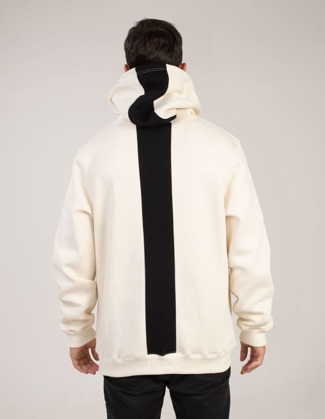 A cream hoodie featuring a contrasting black stripe down the back and a large hood. It has a logo on the front.