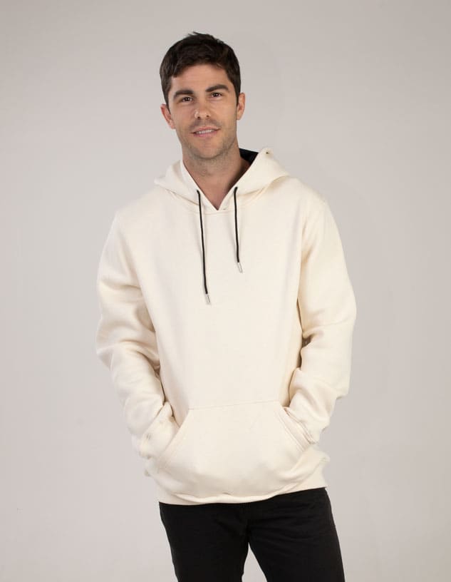 A cream hoodie is worn by a model with hands in pockets, featuring a drawstring and a logo.