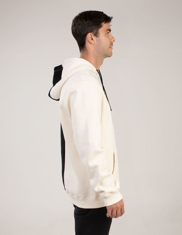 A hoodie in cream and black, featuring a hood and a logo, displayed on a model from the side.