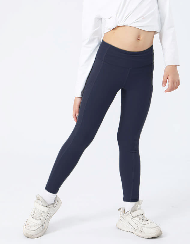 Navy girl’s leggings displayed on a model, paired with a white top and light-coloured sneakers.