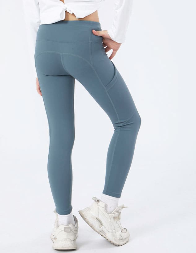 A pair of girl's leggings in a soft blue colour, featuring a fitted design and a waistband, displayed on a model.
