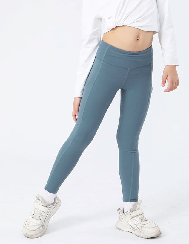 Girl's leggings in a light blue colour, featuring a sleek design and fitted style, paired with white sneakers.