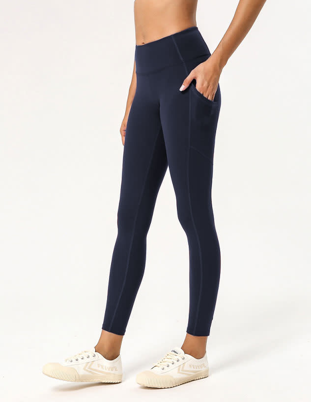 Navy ladies' leggings with side pockets displayed on a model, paired with white footwear. Feature a sleek design.