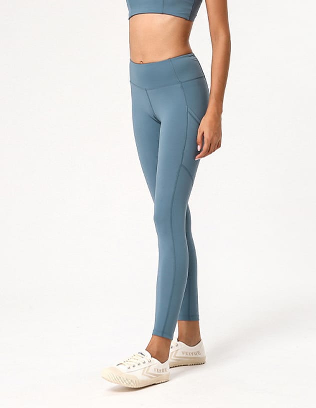 A pair of blue ladies' leggings displayed on a model, featuring a fitted design and a logo.