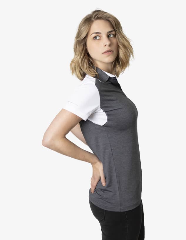 A grey and white polo shirt with a logo, worn by a model posing sideways.
