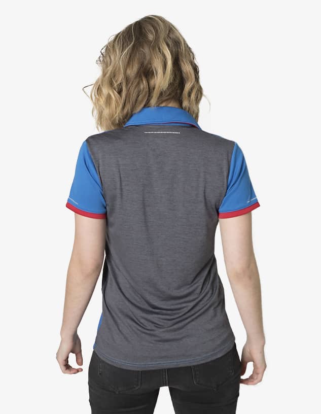 A woman is wearing a grey and blue polo shirt with red accents, featuring a logo on the back.