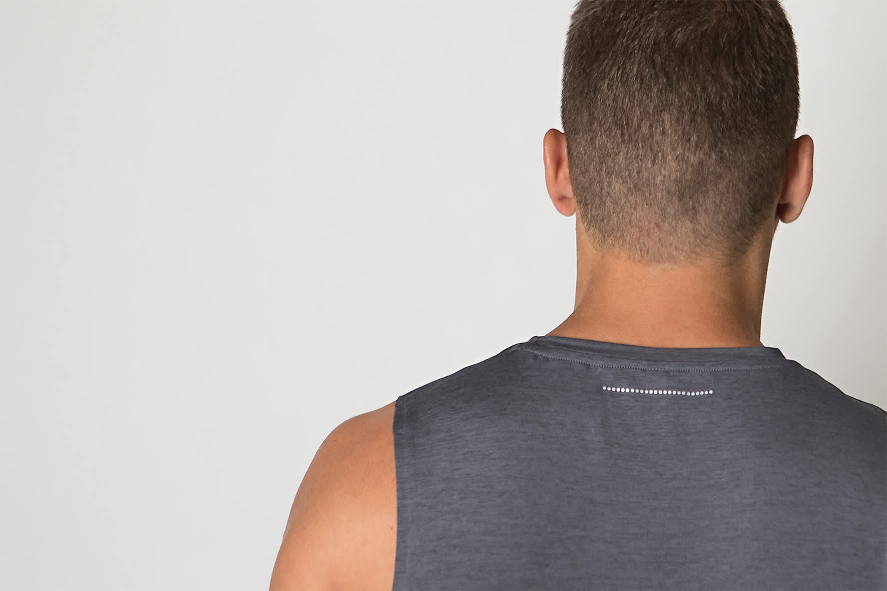 A grey singlet shirt is displayed, featuring a subtle logo at the back and a smooth fabric texture.