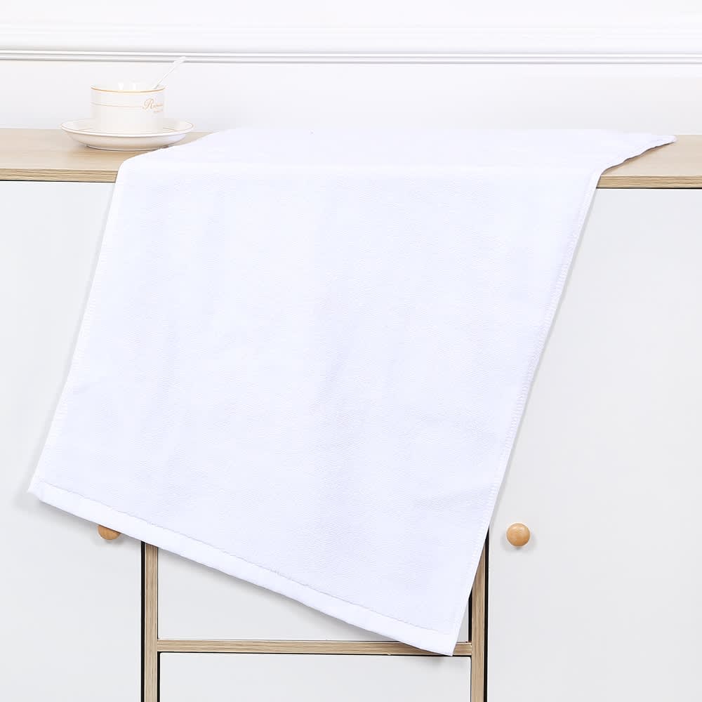A white gym towel draped over a wooden surface, featuring a simple design with a logo.