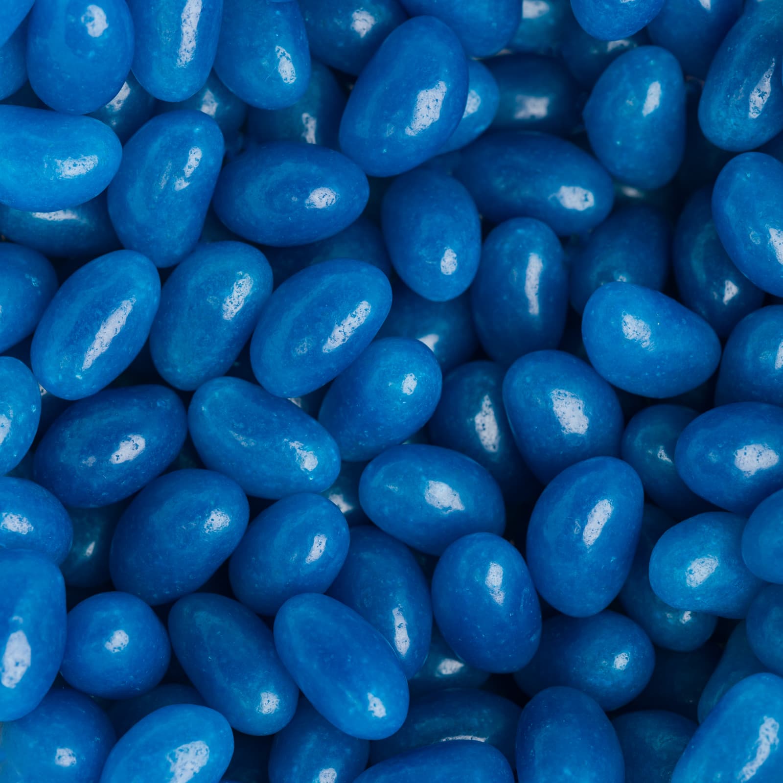 A close-up of vibrant blue jelly beans, featuring a glossy finish and various oval shapes.