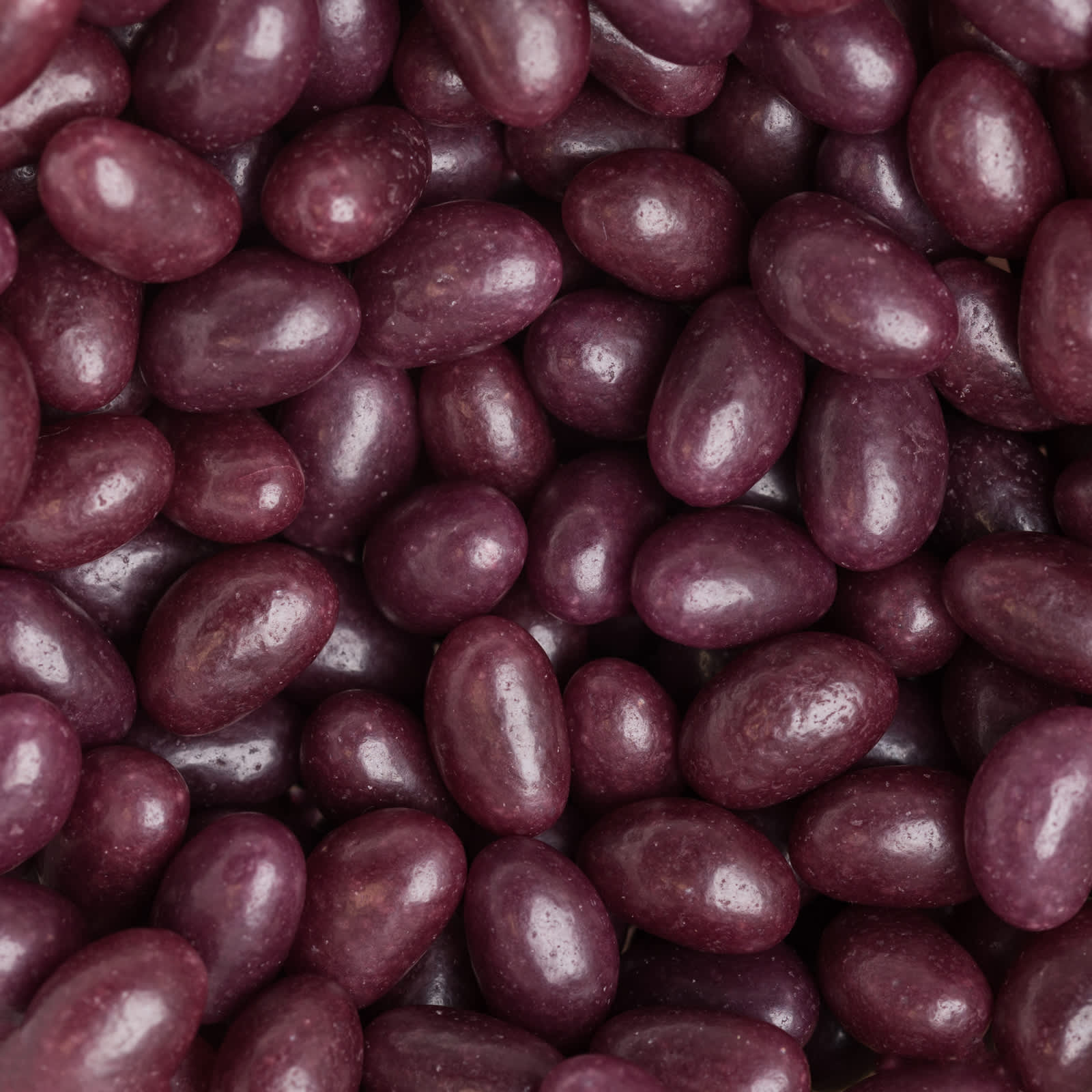 A close-up of glossy purple mini jelly beans, showcasing their smooth, round shapes and vibrant colour.