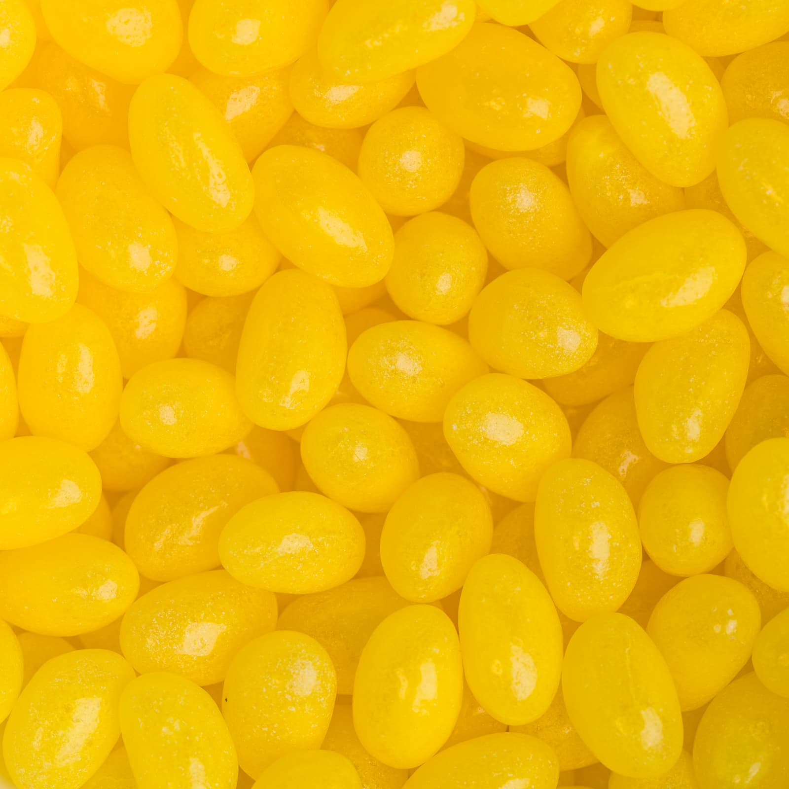 Bright yellow jelly beans in a clustered arrangement, featuring a glossy finish. The image has a branding logo present.