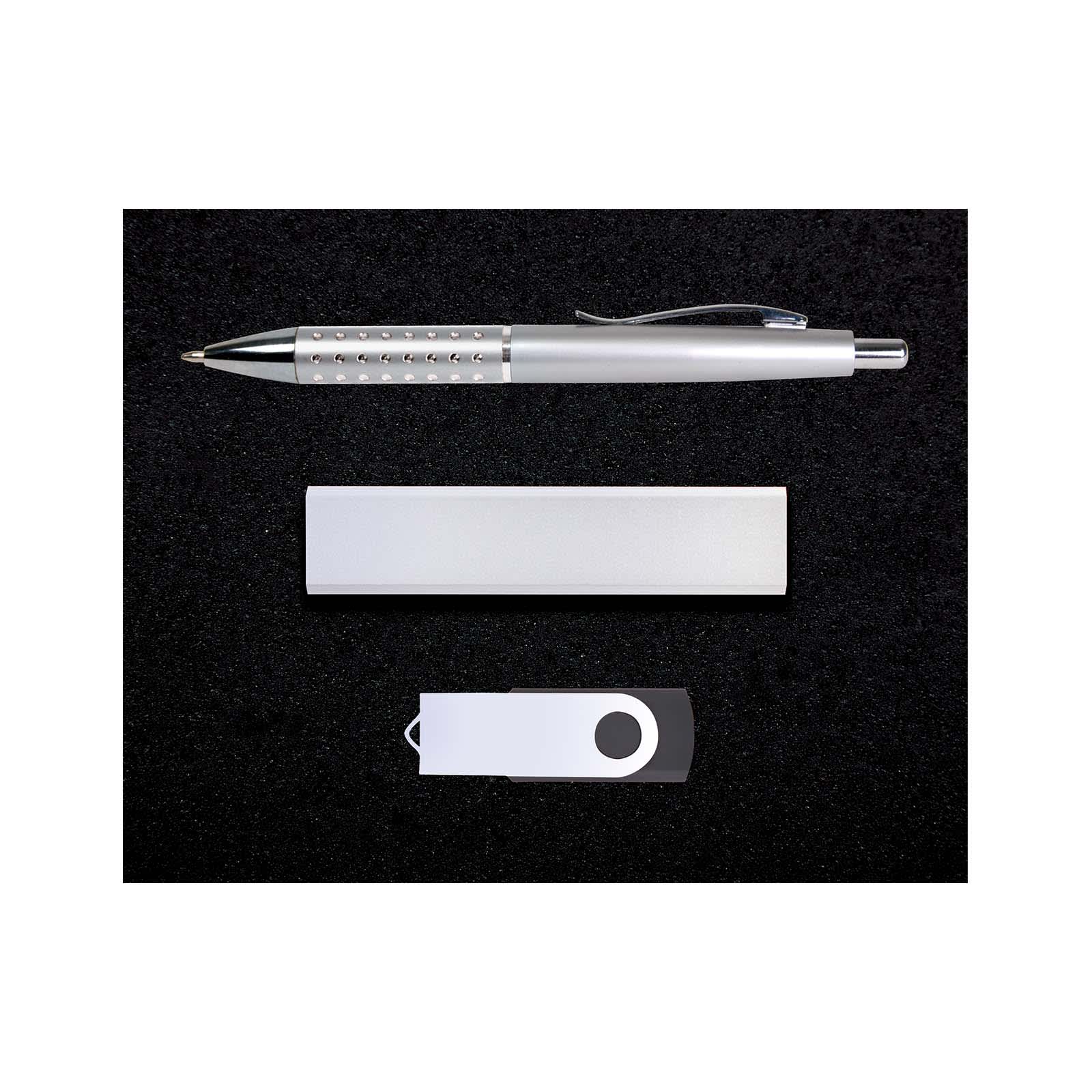 A silver pen, a silver USB drive, and a silver cardholder arranged on a black surface.