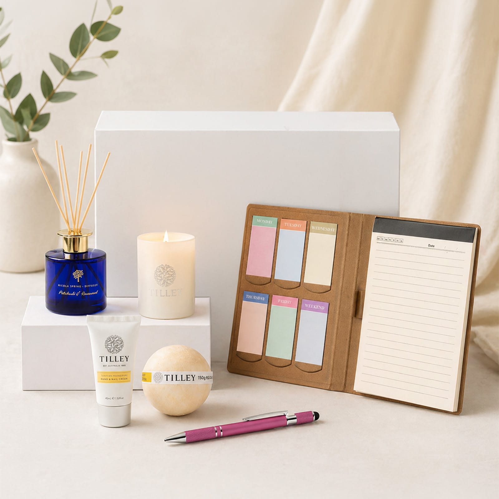 A collection of home and living items including a blue aromatherapy diffuser, a candle, a notebook, and pastel sticky notes.