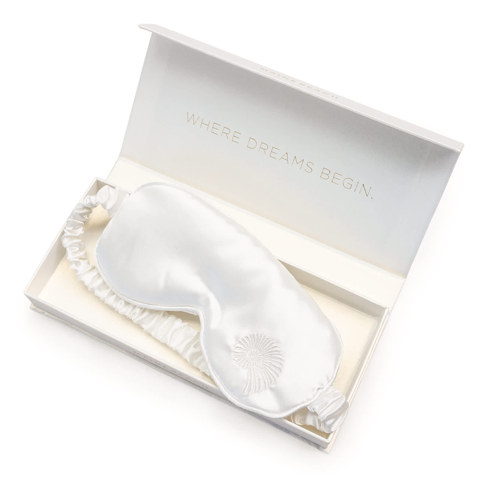 A white silk eye mask in a decorative open box. The box has a subtle logo.