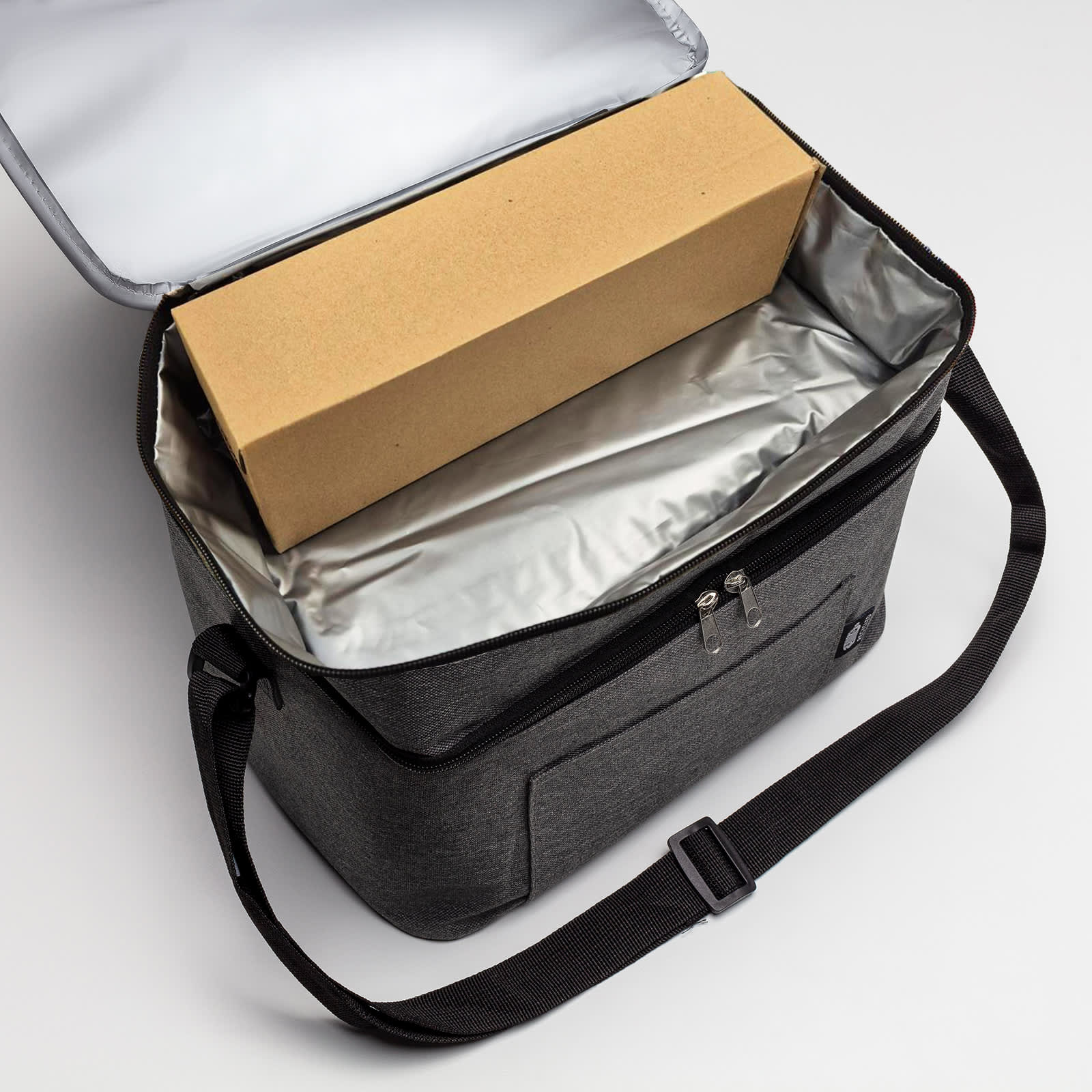 A grey cooler bag with a silver lining, containing a plain cardboard box inside.