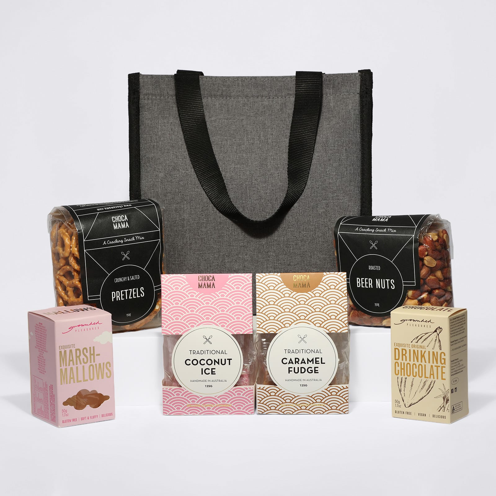 A grey cooler bag with assorted snacks: pretzels, beer nuts, marshmallows, traditional coconut ice, caramel fudge, and drinking chocolate.
