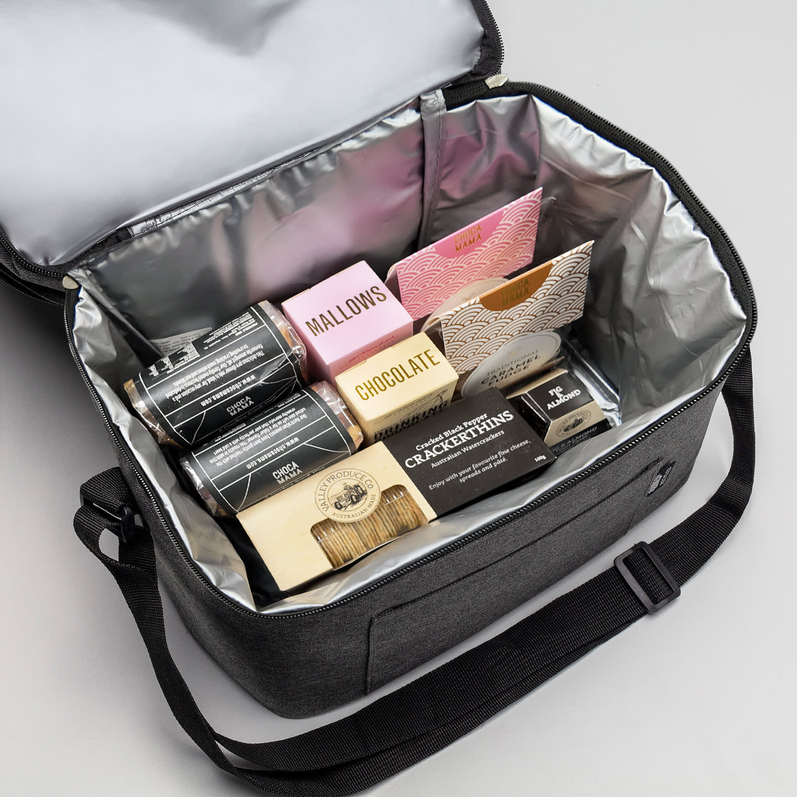 A grey insulated bag containing various snacks, including chocolates, crackers, and marshmallows.