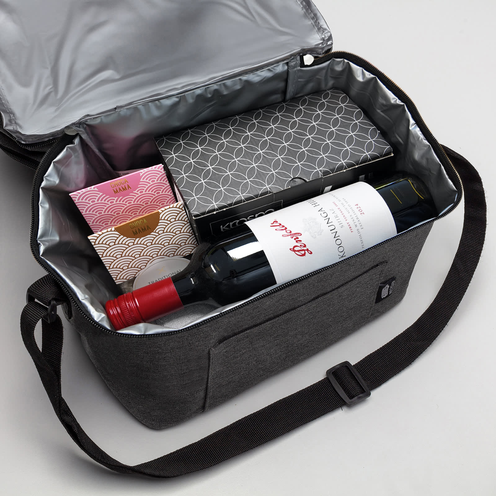 A drink bottle bag in grey containing a bottle of red wine and two other boxed items, with a silver interior.