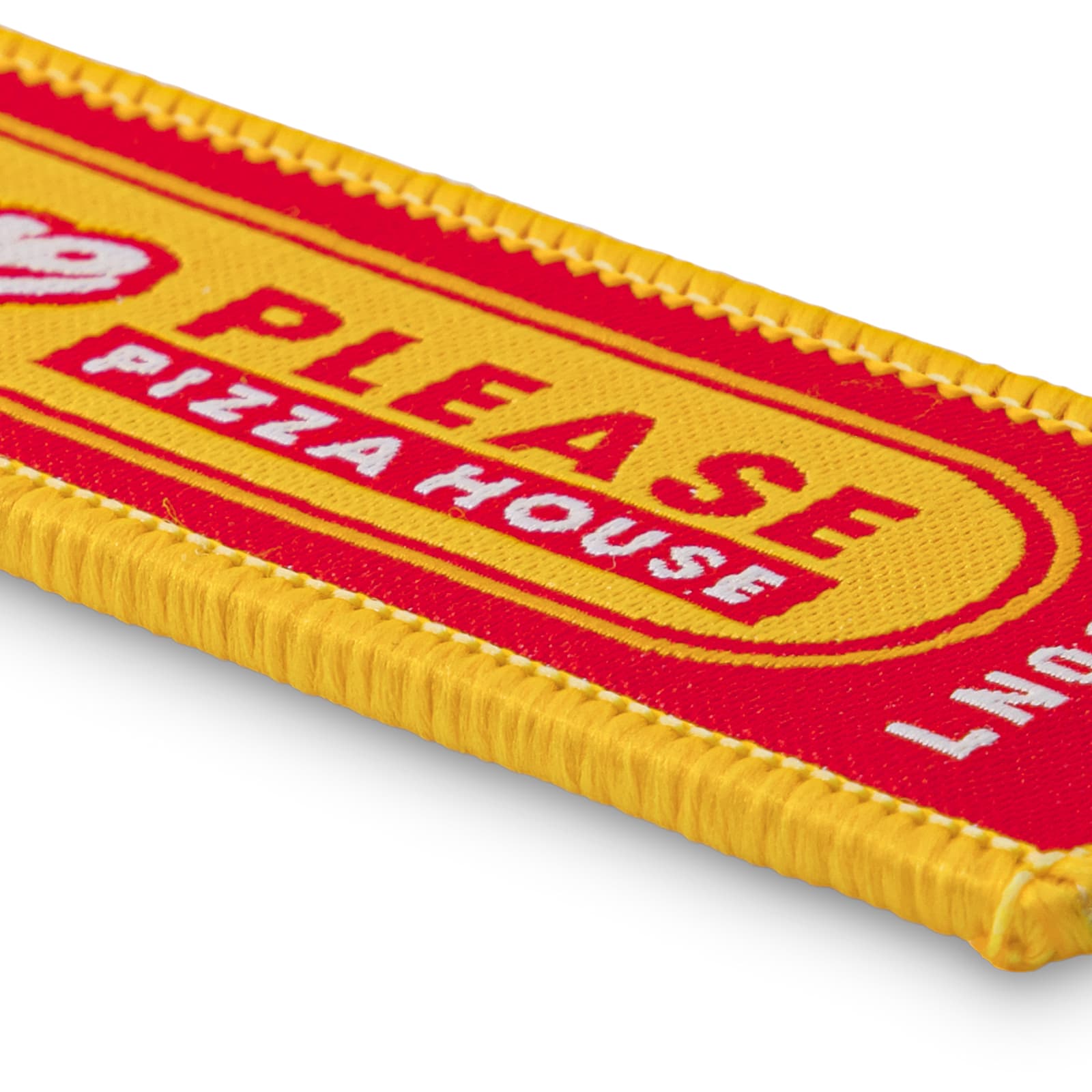 A woven keytag in red and yellow with a branded logo and text design.