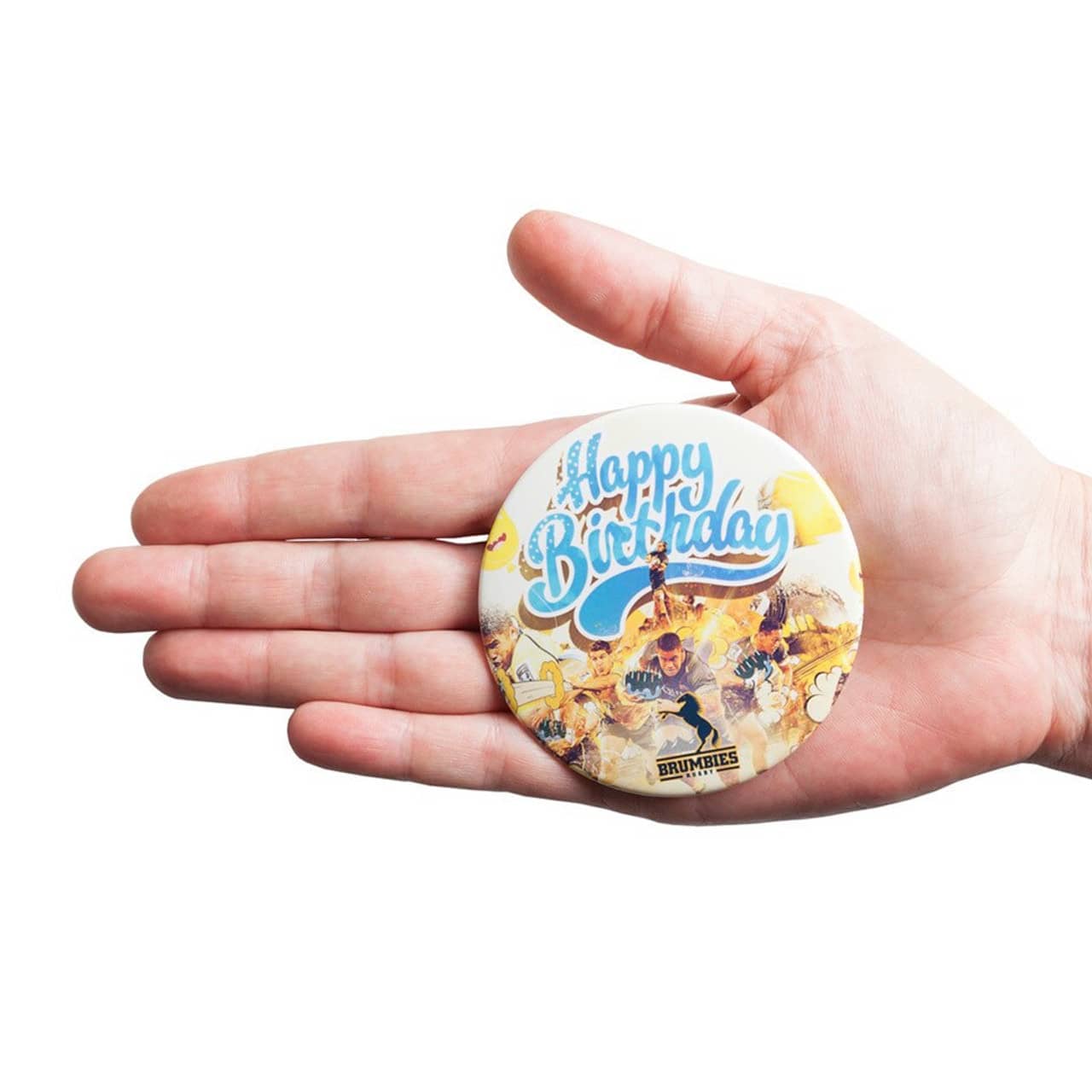 A round badge held in hand, featuring colourful artwork and a logo at the bottom.