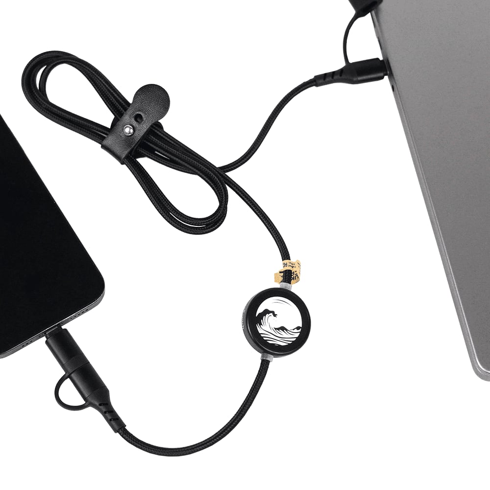 A black charging cable with a circular connector, linking a device to a laptop, featuring a logo.