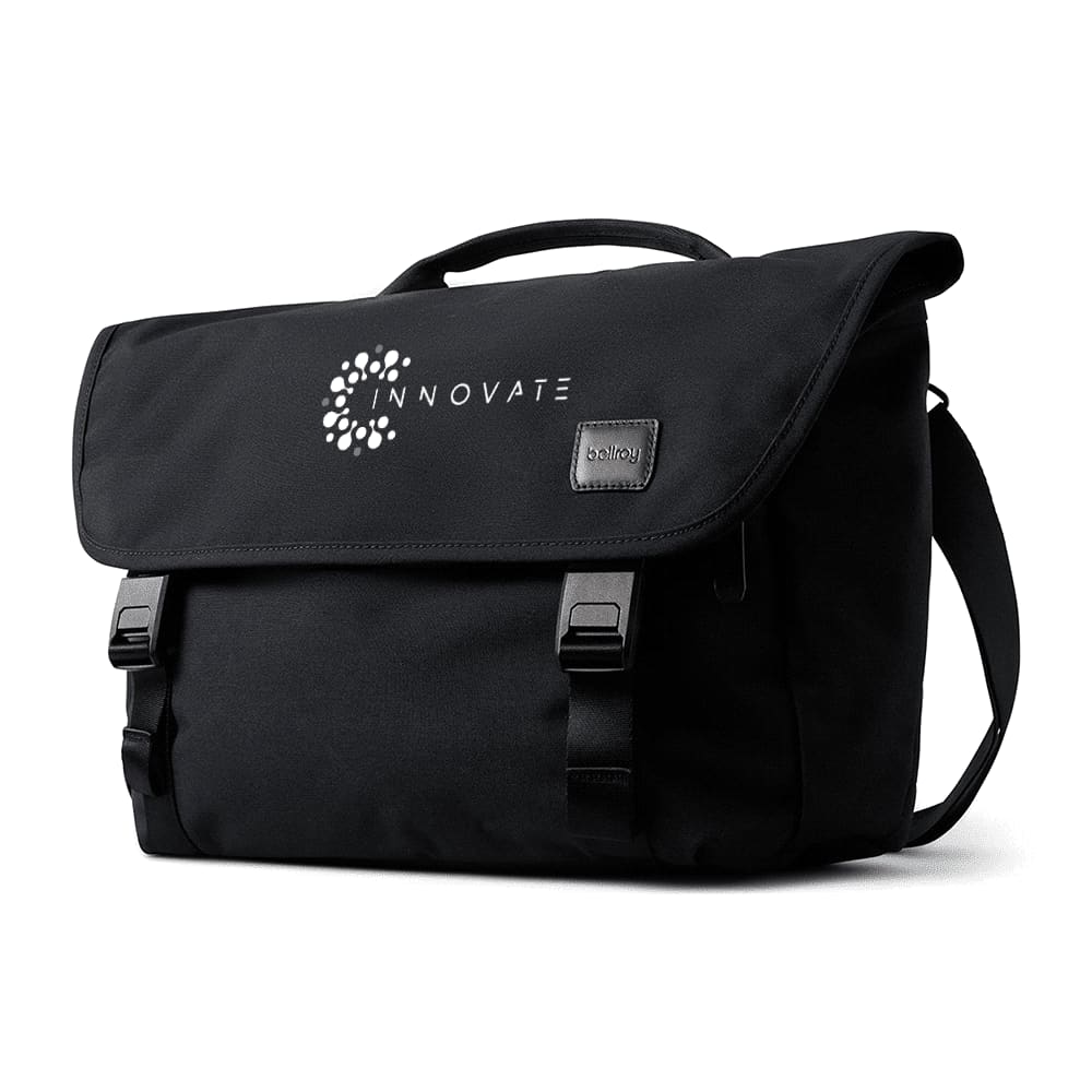 A black satchel bag with a flap closure, featuring straps, a handle, and an embedded logo.