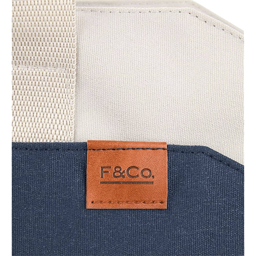 A navy and cream tote bag featuring a leather tag with branding and sturdy woven straps.