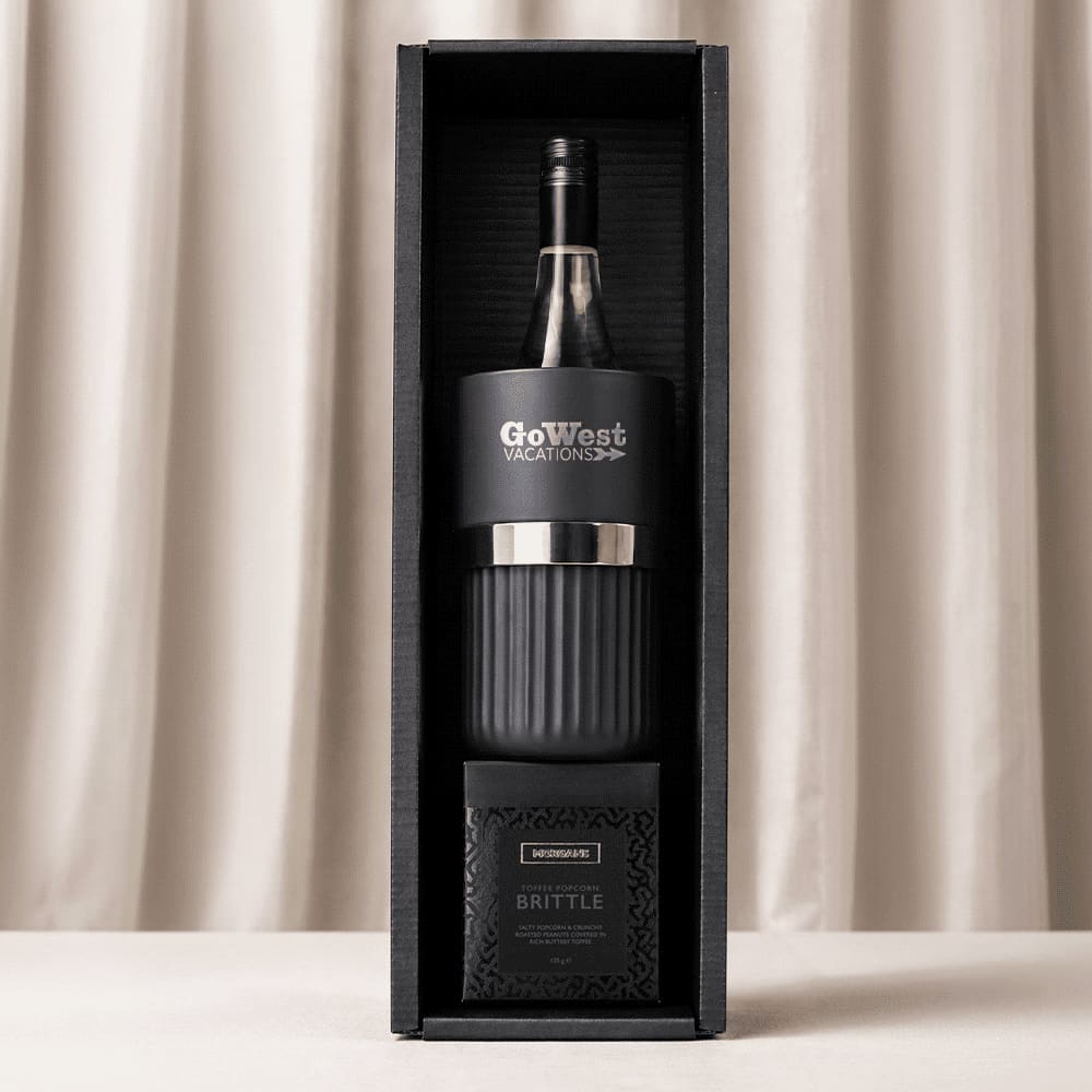 A black wine bottle cooler, a glass tumbler, and a box of brittle, all packaged in a stylish gift box.