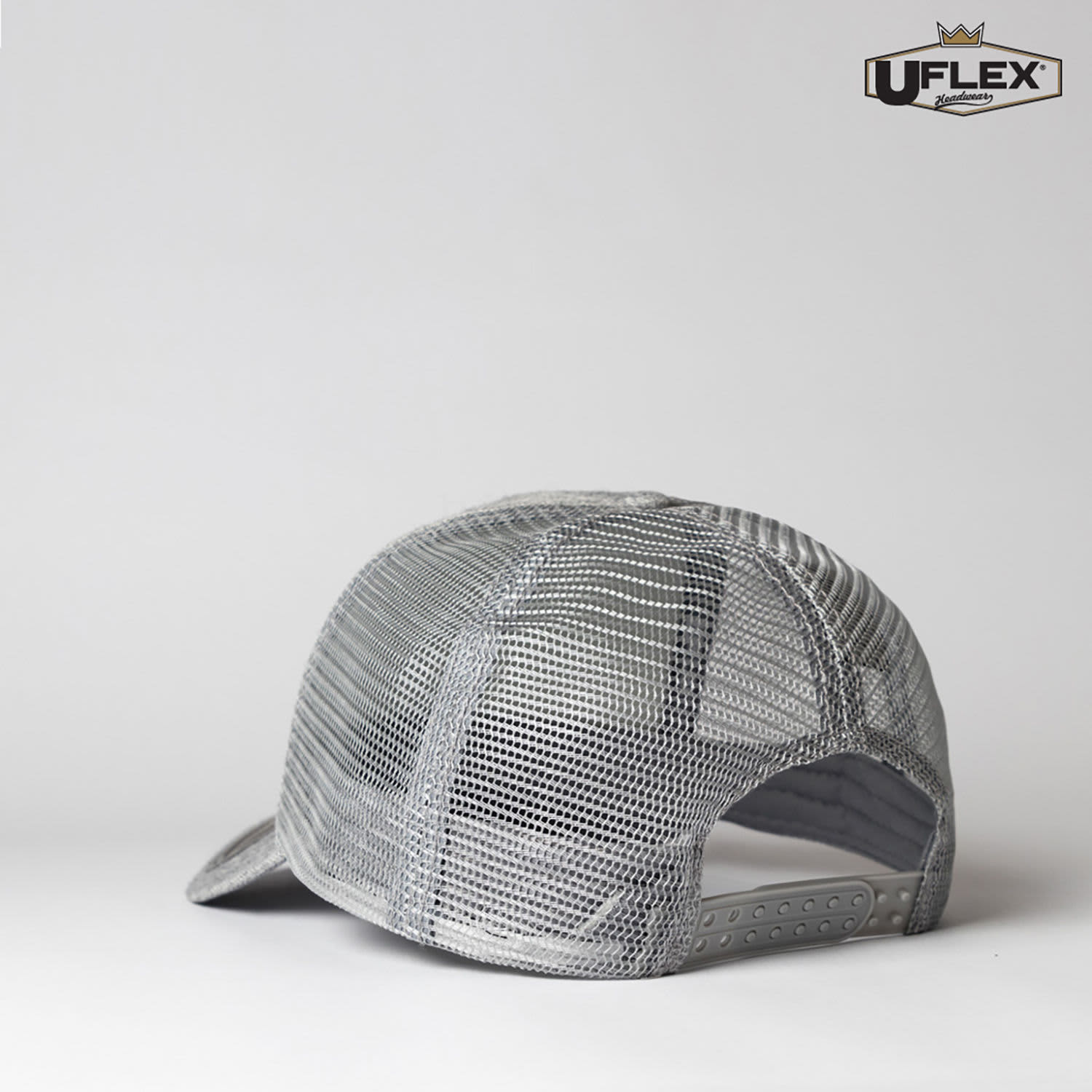 A grey Snap Back Trucker cap with a mesh design and an adjustable strap at the back. It features a logo on the side.