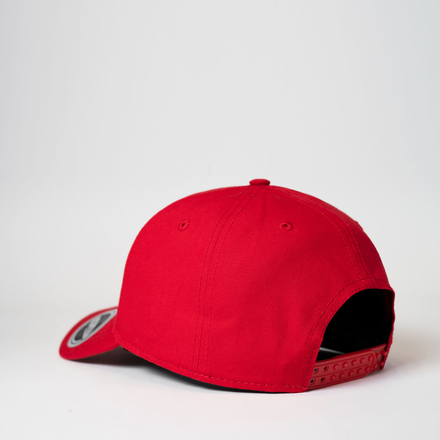 A red 6 panel baseball cap featuring a back adjustable strap and a branded logo on the side.