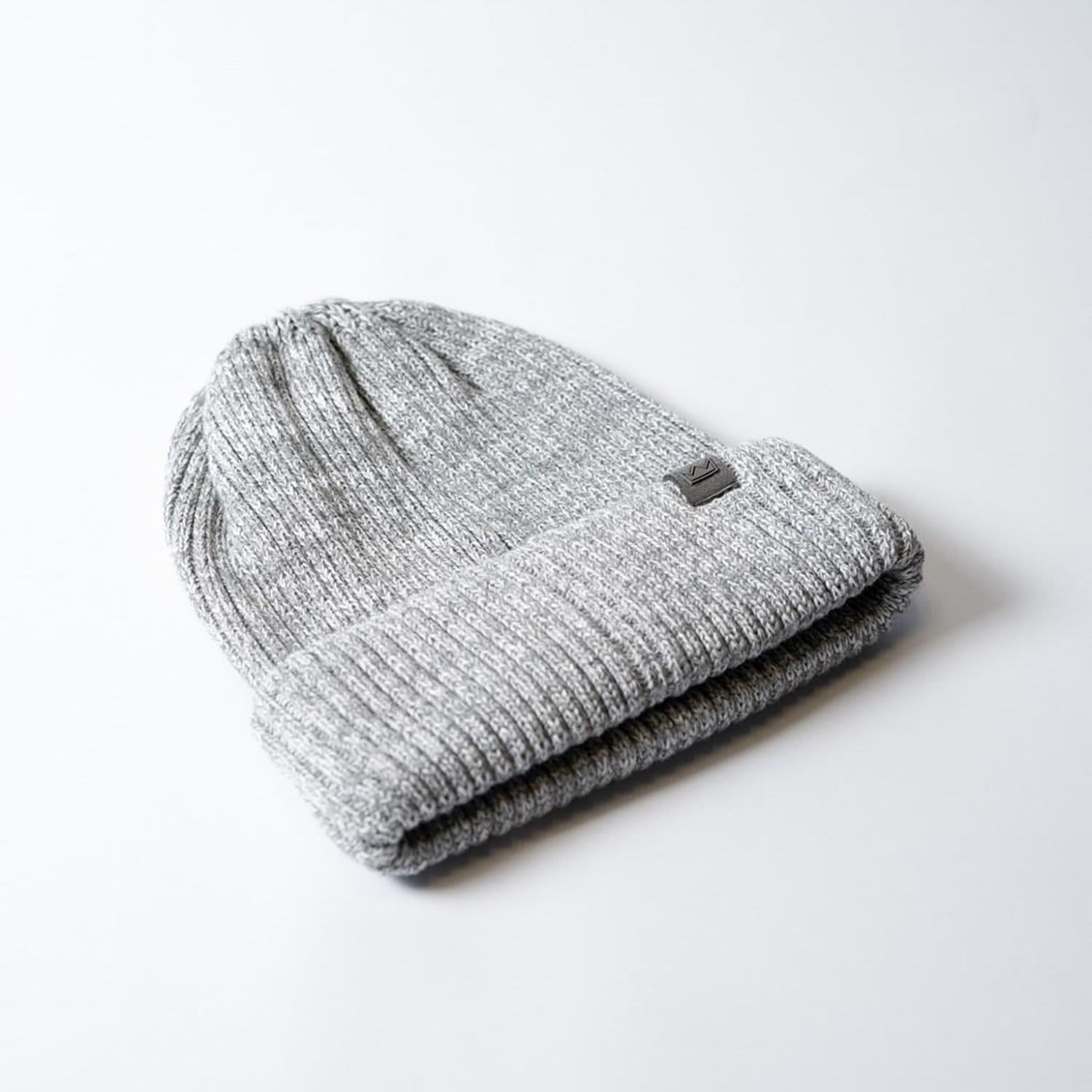 A grey knitted beanie with a folded cuff and a small logo.