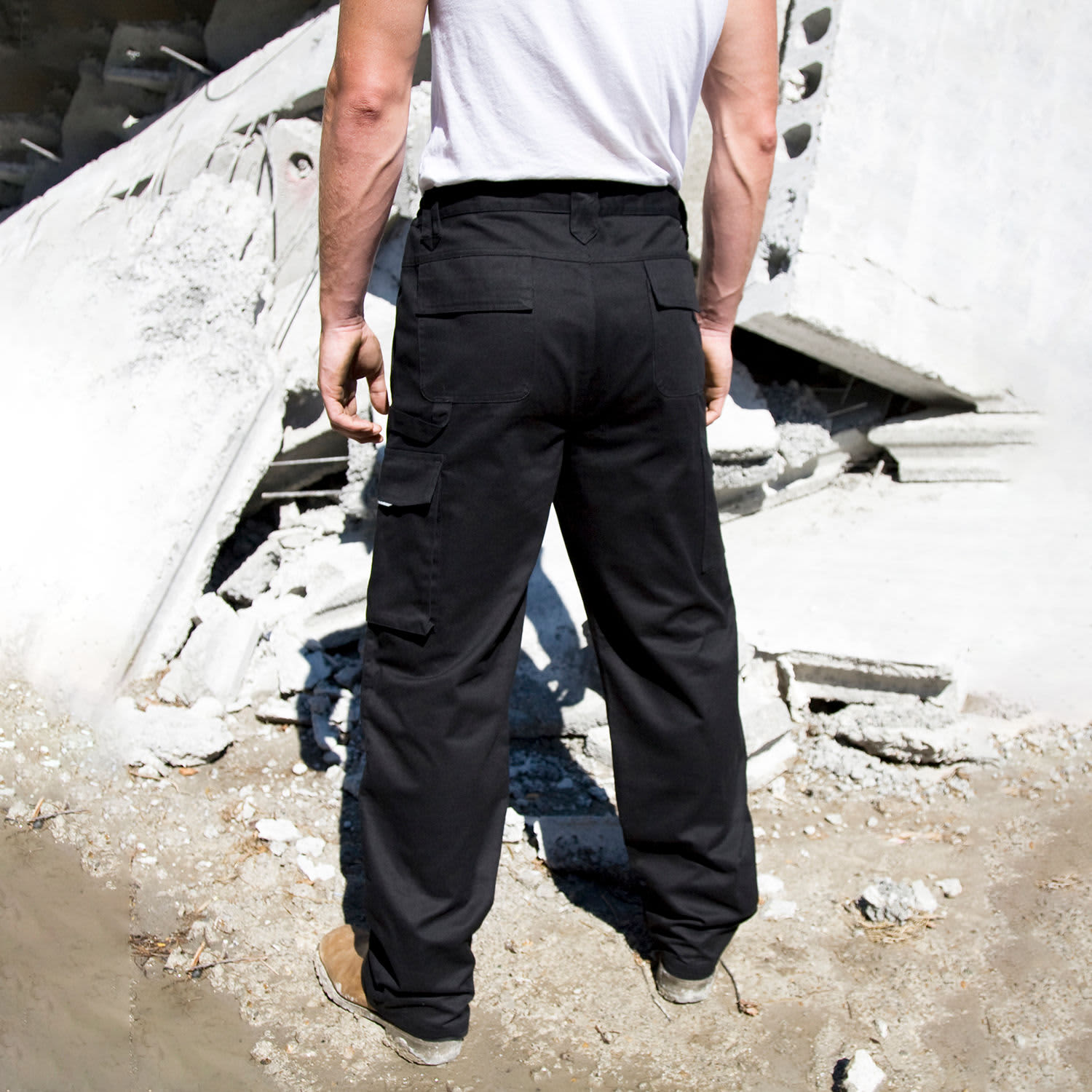 Black action trousers featured against a construction backdrop, showcasing functional pockets and a durable design.