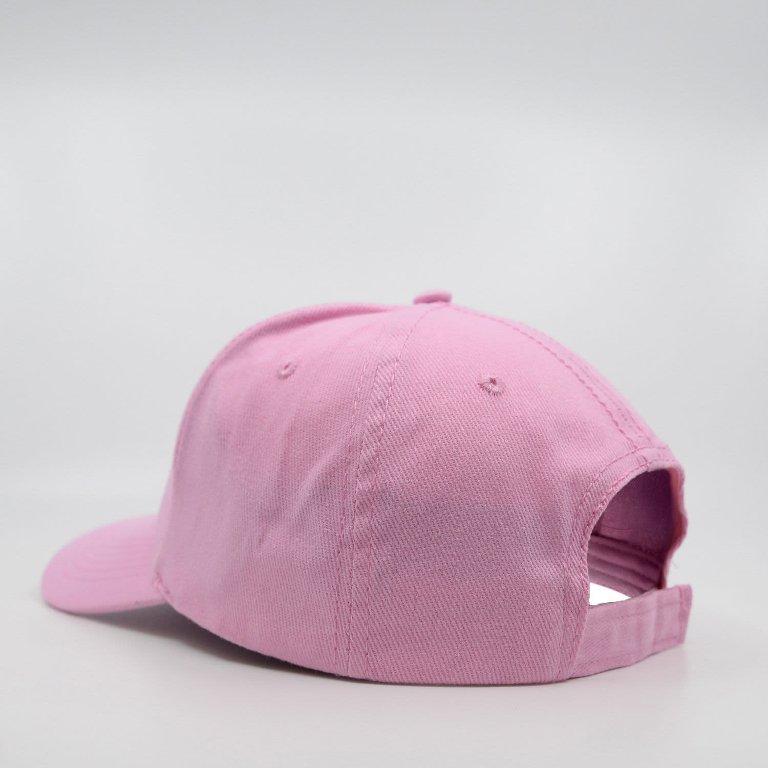A pink six-panel brushed cotton cap with a curved peak and an adjustable strap at the back.
