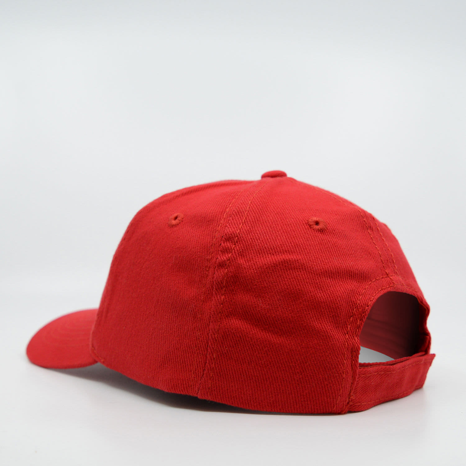 A red six-panel baseball cap made of brushed cotton, featuring a curved peak and an adjustable back.